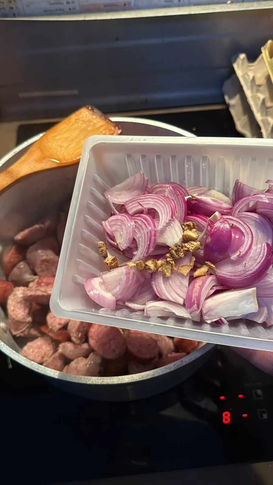 Les oignons émincés et le gingembre rejoignent les saucisses.